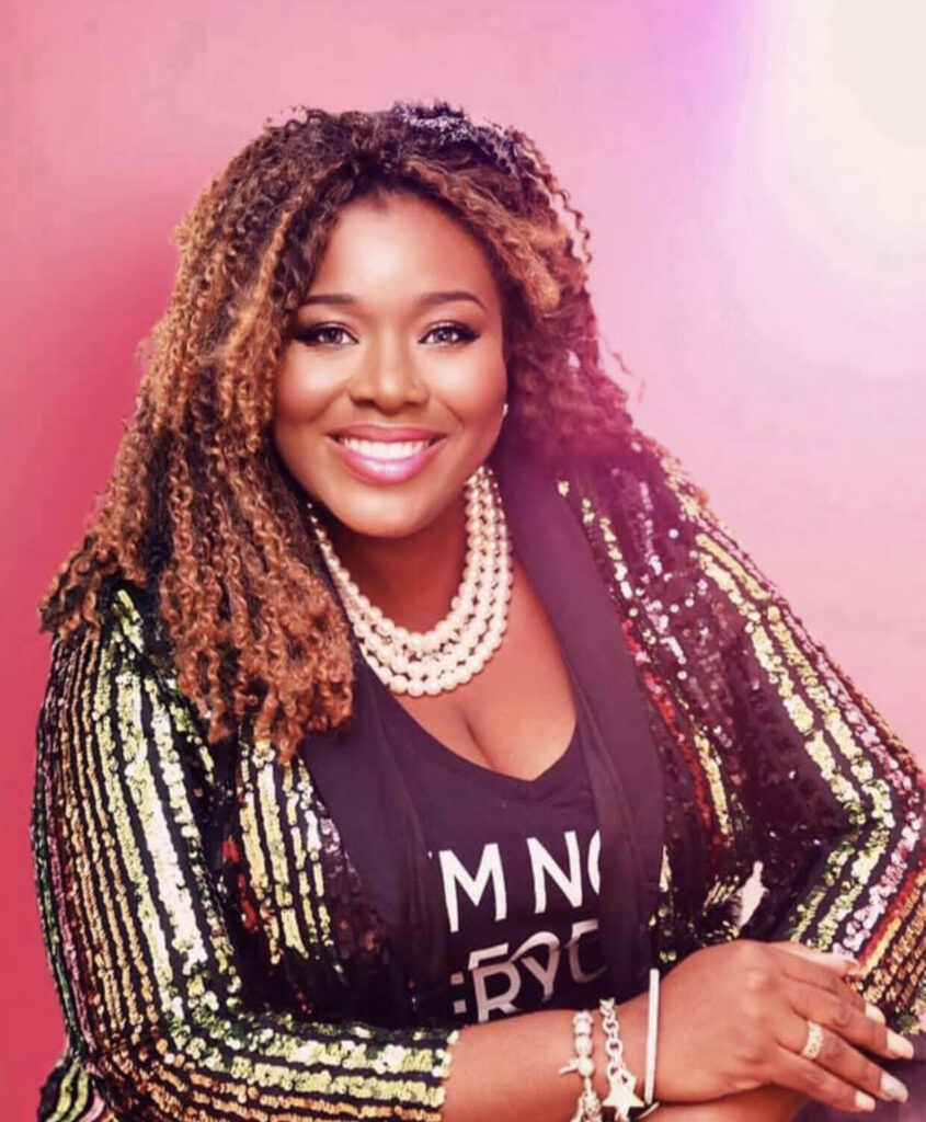 Photo of Dr. Zakiya Mabery, a Black woman with curly brown hair in pearls and a shiny blazer, against a pink background.