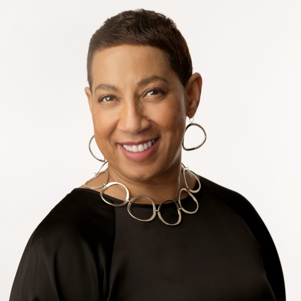 Satonya Fair, a Black woman with low cut straight black hair, wearing a black blouse, silver earrings, and a matching necklace. She is smiling brightly at the camera.