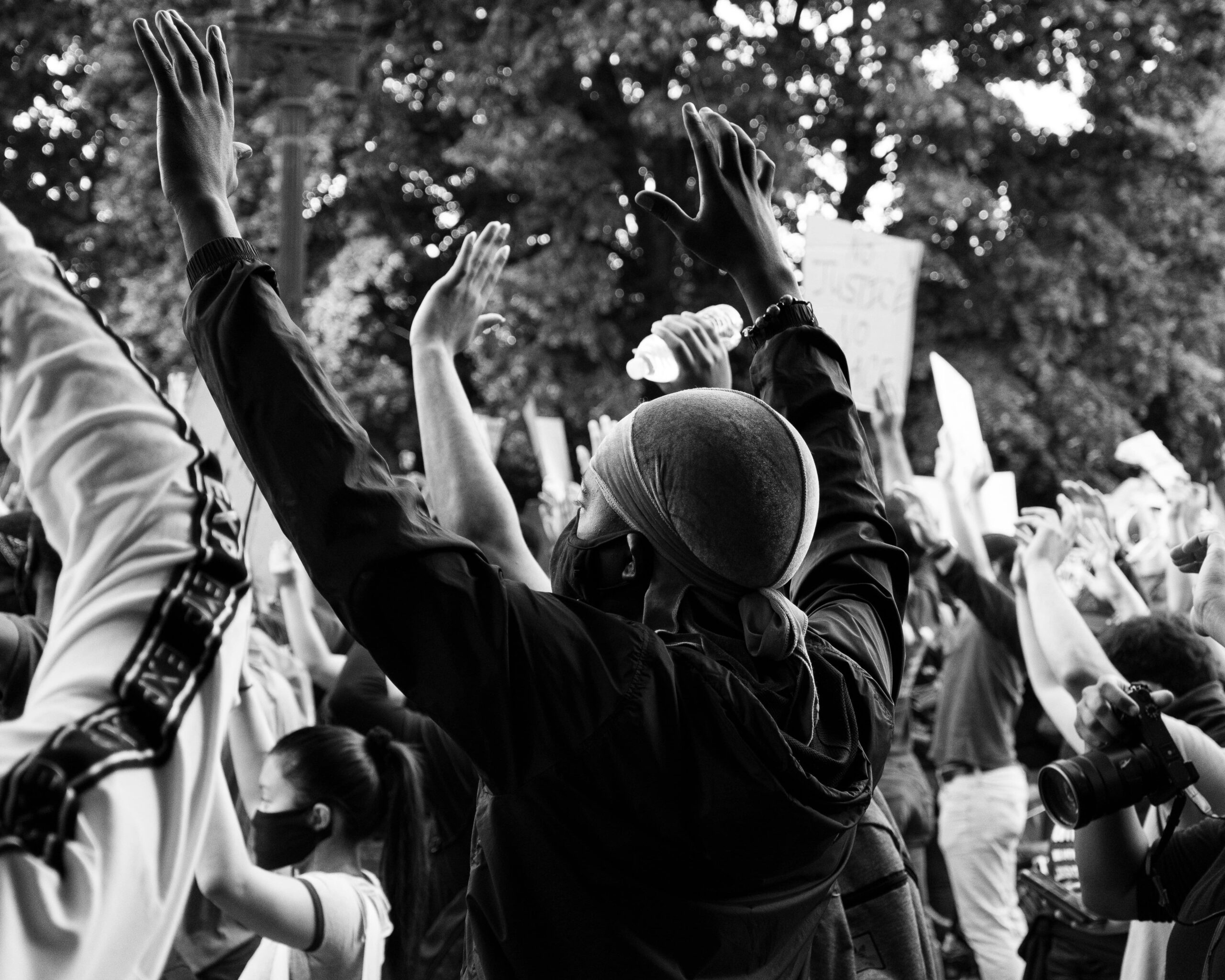 A black and white photo of a diverse group of people with their hands up during a Black Lives Matter protest.
