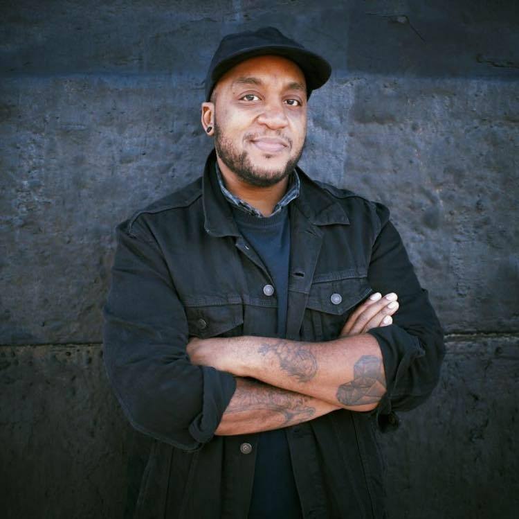 Gabriel Foster, a Black queer trans man in a black hat and a black jacket.