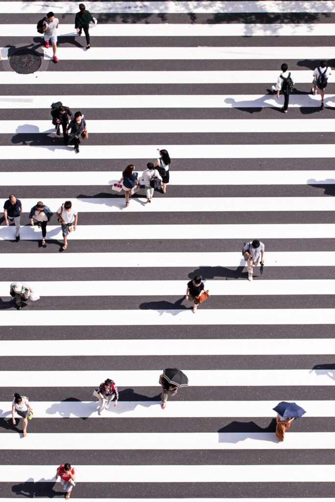 Aerial view of group of people crossing gray and white pedestrian lane.