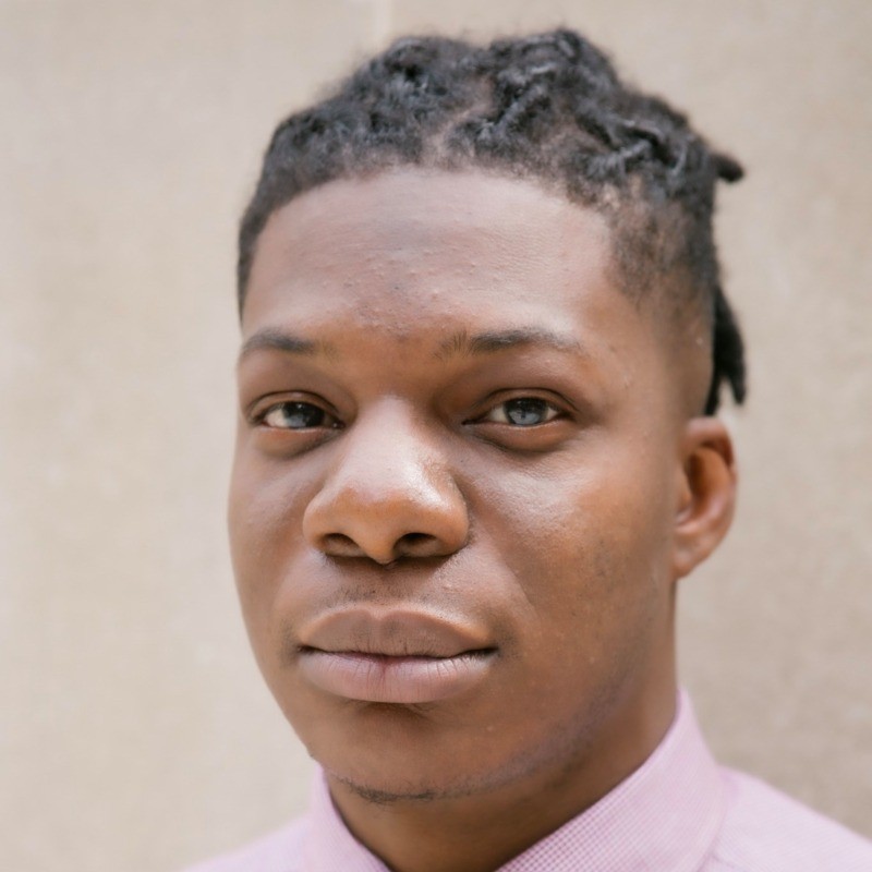 Marq Mitchell wears a pink shirt with braids in his hair.